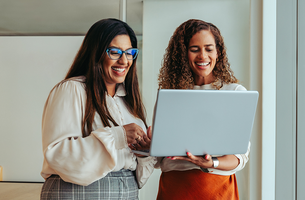 Compañeras de equipo colaborando en un proyecto usando un portátil.
